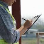 Home inspector recording findings on a clipboard after completing a buyer's home inspection