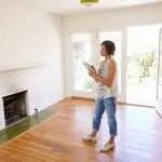Real estate agent with a tablet walking through an empty home to schedule a home inspection