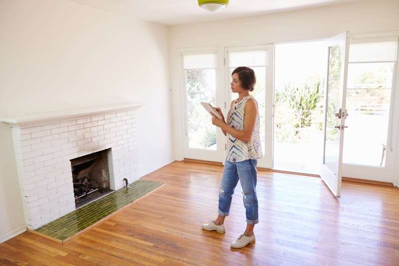 Real estate agent with a tablet walking through an empty home to schedule a home inspection